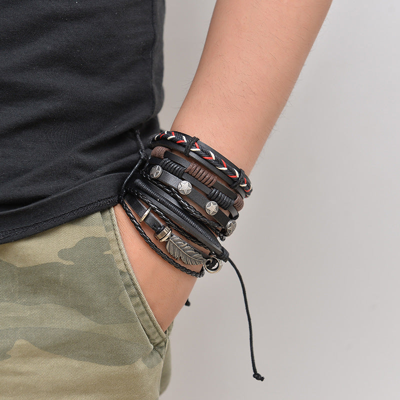 Person wearing multiple leather bracelets with metal accents on a neutral background