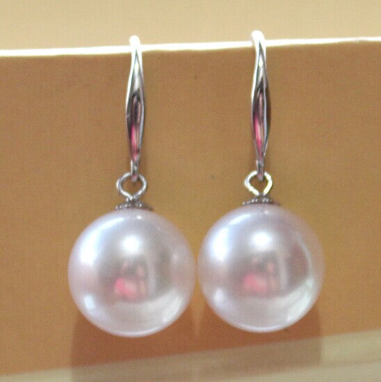 Pearl earrings with silver hooks on a beige background