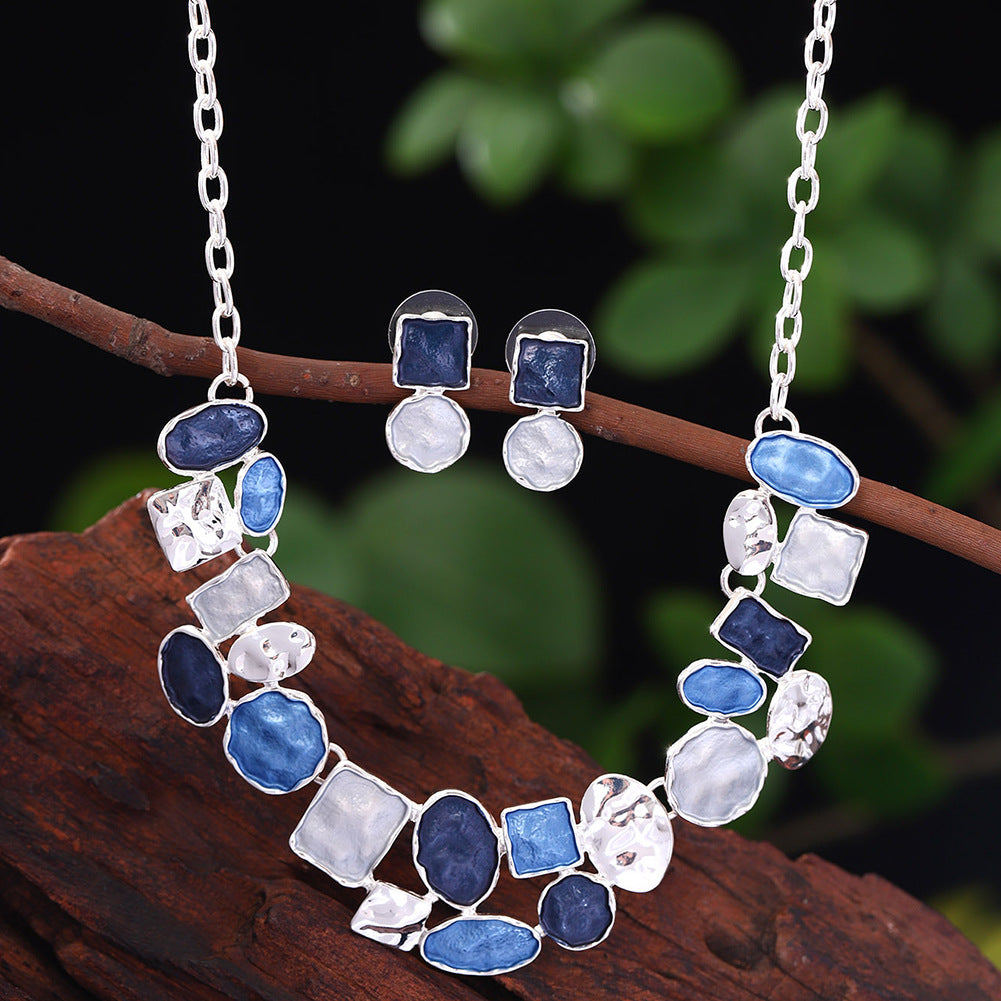 Jewelry set with necklace and earrings on a branch with a blurred green background