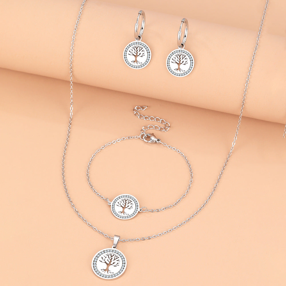 Silver jewelry set with tree-of-life design on a beige background
