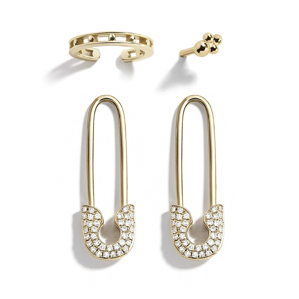 Gold safety pin earrings with clear gemstones on a white background