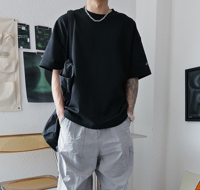 Person wearing a black t-shirt and light gray pants in an indoor setting.