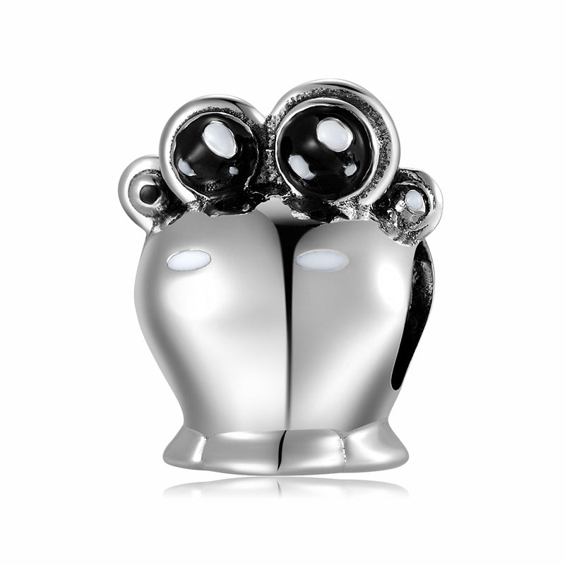 Silver charm with black and white stones on a white background