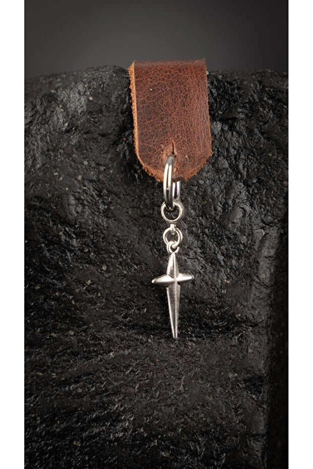 Silver dagger pendant on a leather strap against a dark stone background