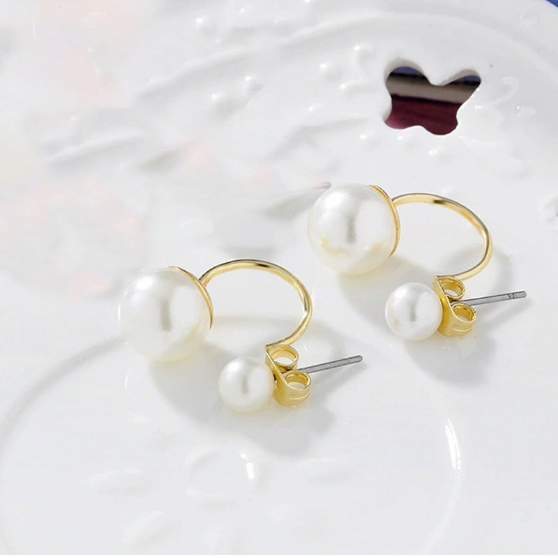 Pearl earrings with gold hooks on a white surface