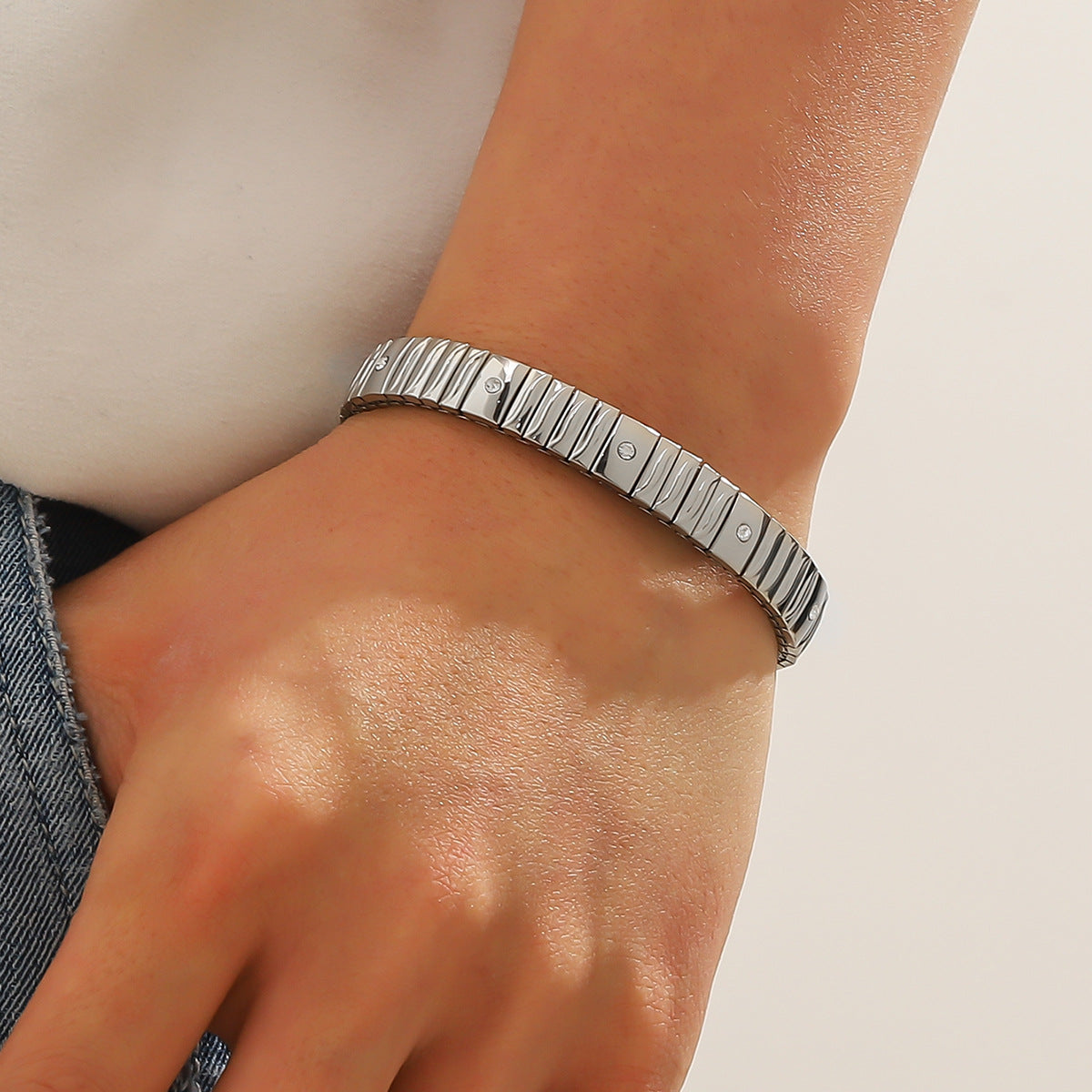 Silver bracelet on a wrist with a neutral background