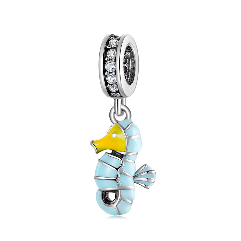Silver charm shaped like a seahorse with blue body and yellow tail on a white background
