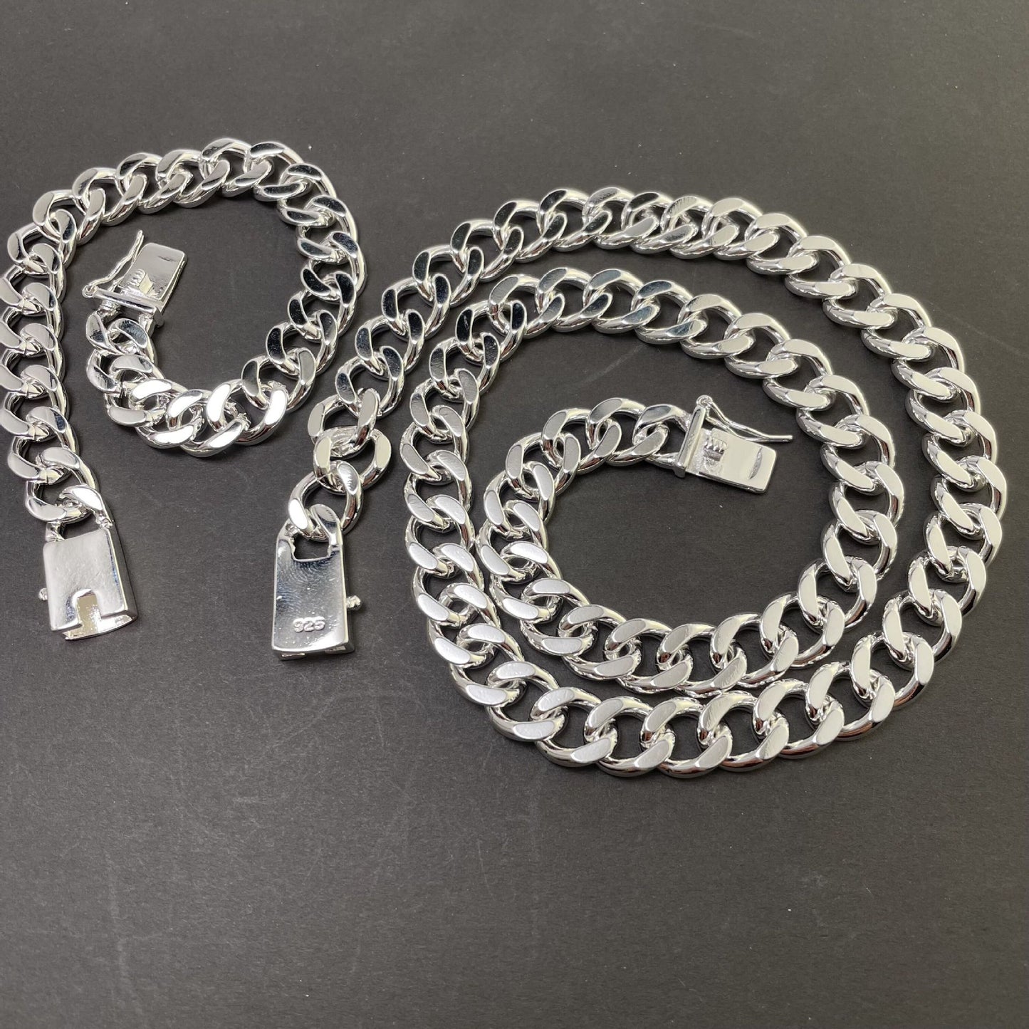 Silver chain necklace and bracelet on a dark surface
