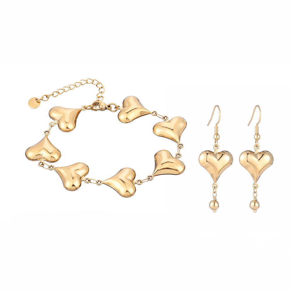 Gold heart-shaped bracelet and earrings on a white background