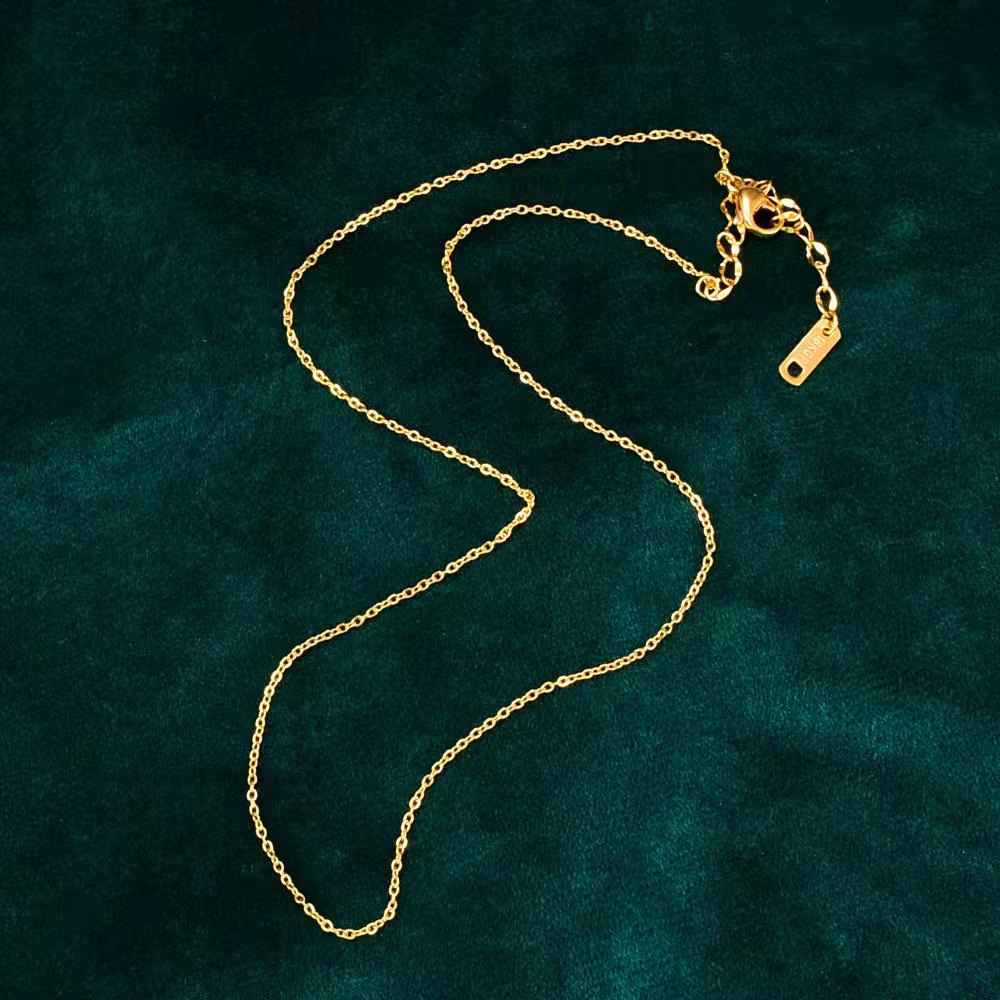 Gold chain necklace on a dark green textured background