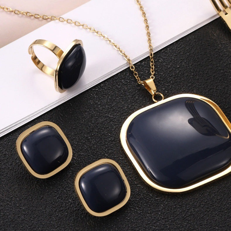 Jewelry set with black stones and gold accents on a dark surface