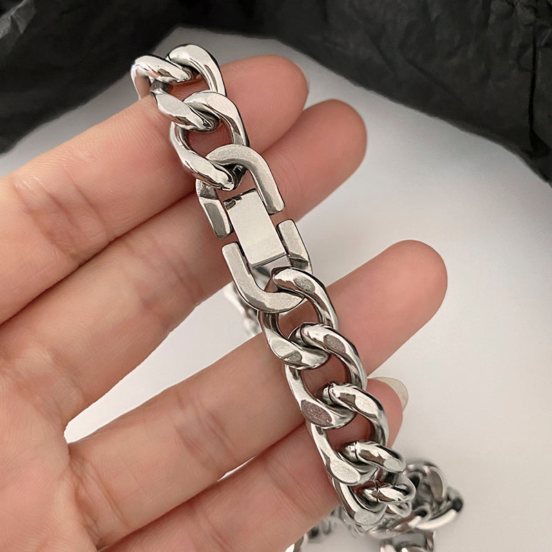 Silver chain bracelet held in a hand against a neutral background