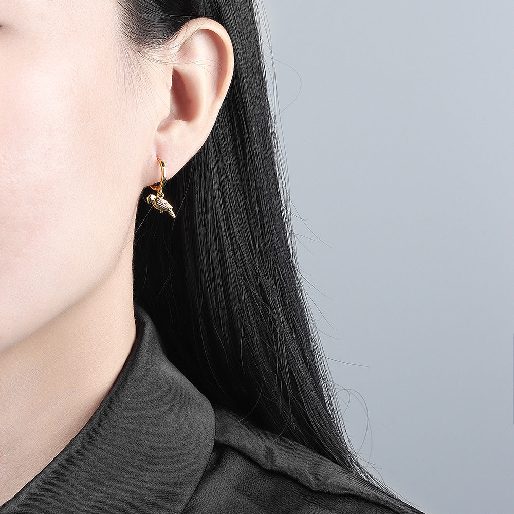 Close-up of a person wearing gold earrings with a gray background