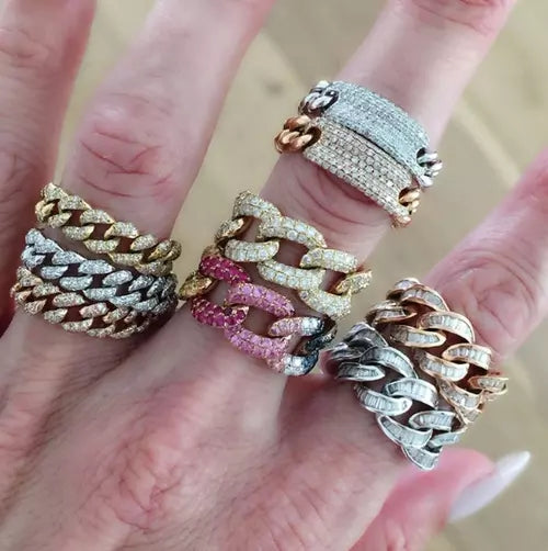 Hand wearing multiple diamond-encrusted rings on a blurred background