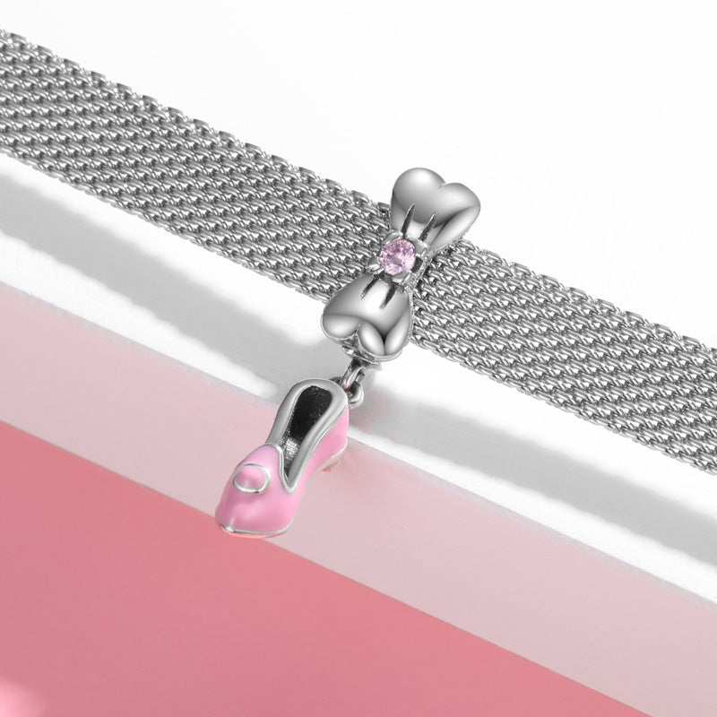 Silver bracelet with pink shoe and bow charm on a pink and white background