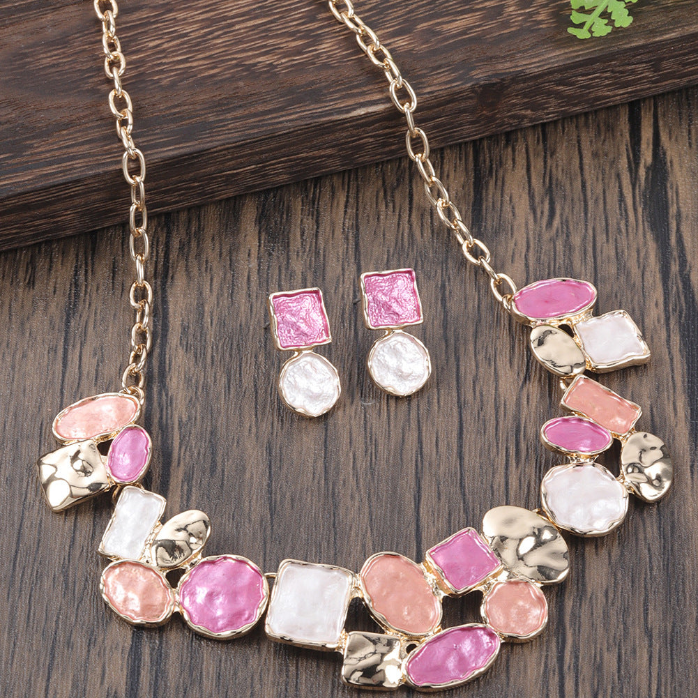 Necklace and earrings with pink and white stones on a wooden surface