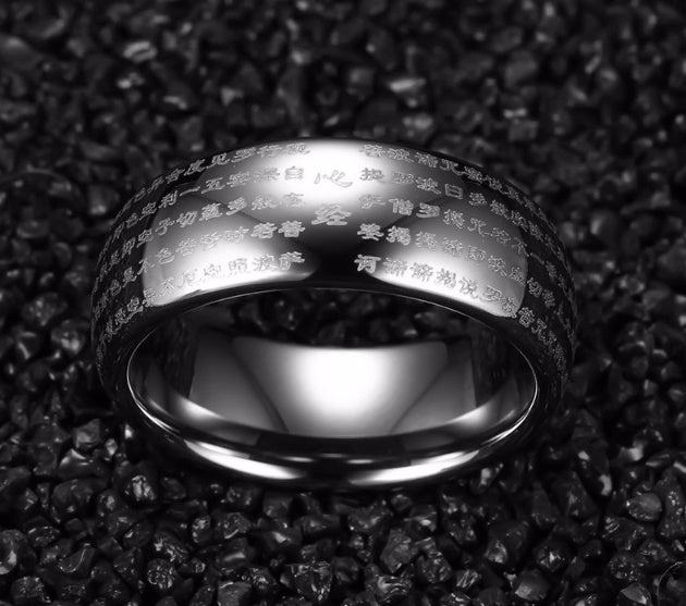 Silver ring with engraved text on a dark textured background