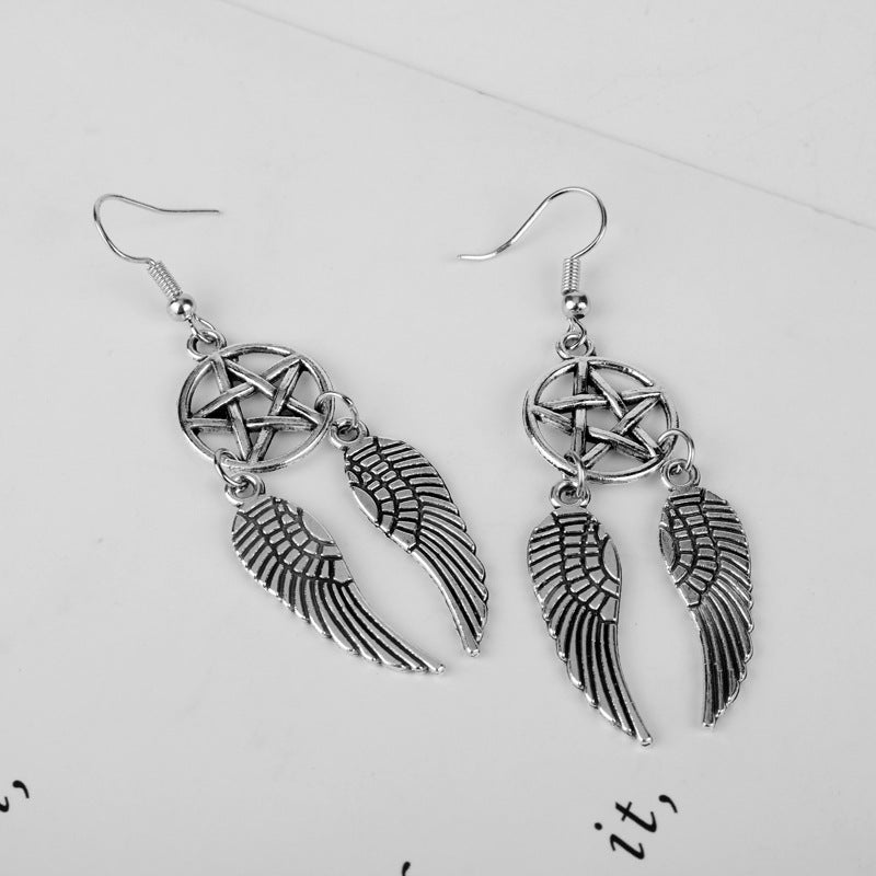 Silver wing-shaped earrings with a pentagram design on a light gray background
