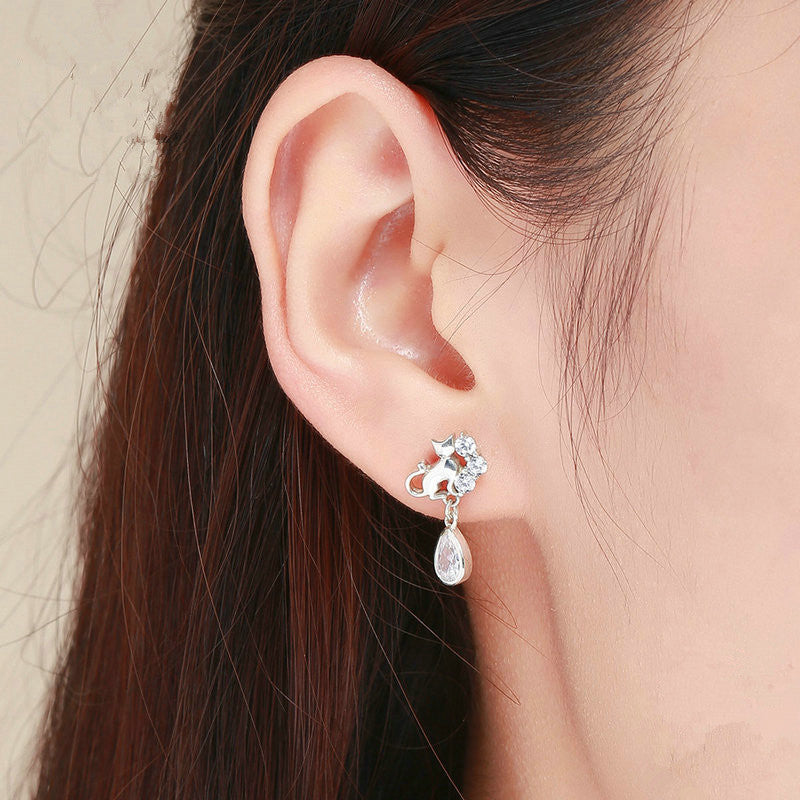 Close-up of an ear wearing a silver earring with a teardrop design.