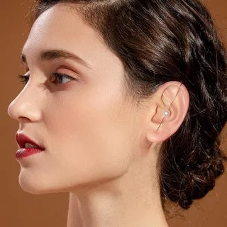 Close-up of a woman wearing a small earring with a brown background