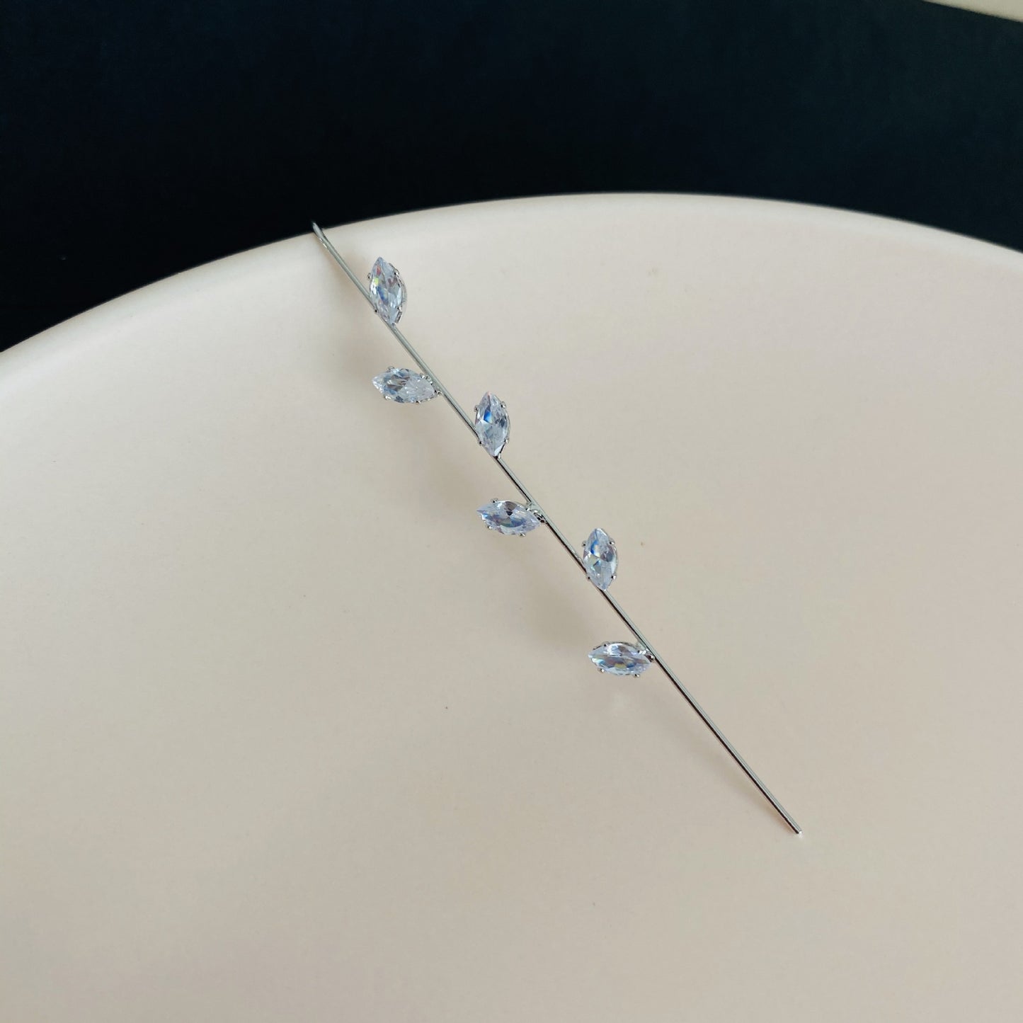 Silver hairpin with blue gemstones on a beige surface