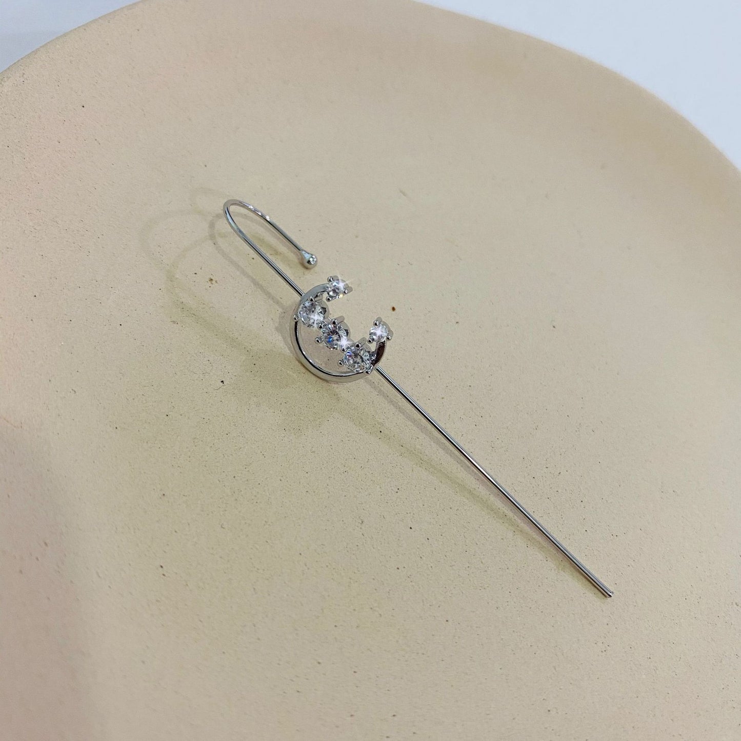 Silver hair pin with a decorative element on a beige surface