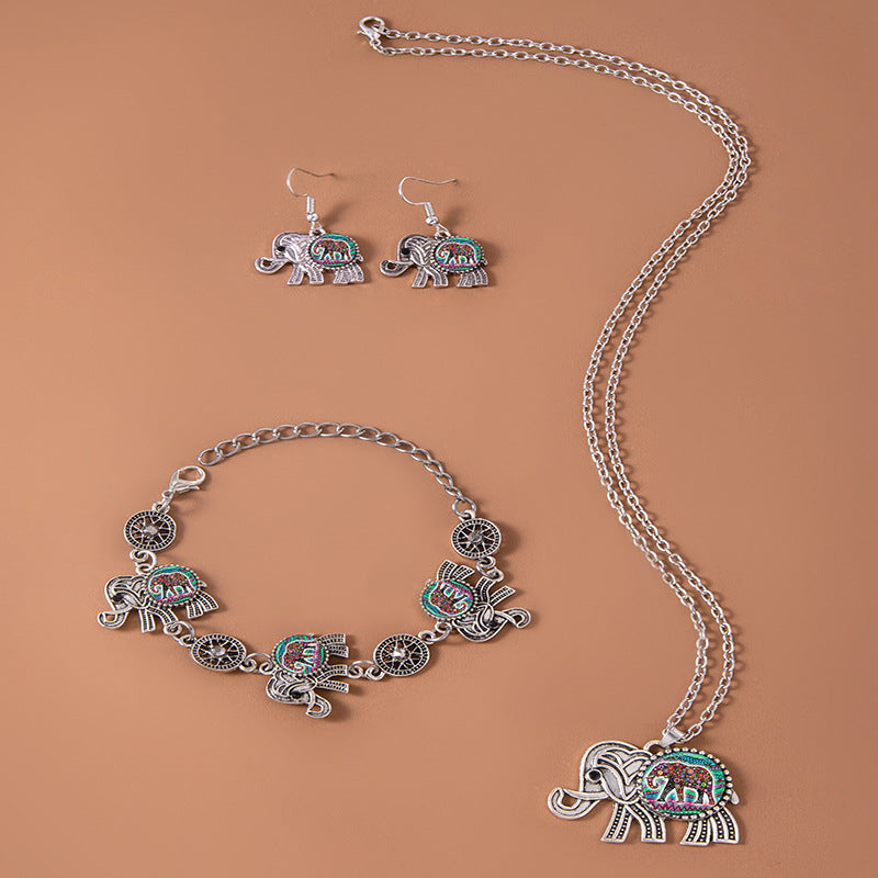 Jewelry set with elephant-themed necklace, bracelet, and earrings on a brown background
