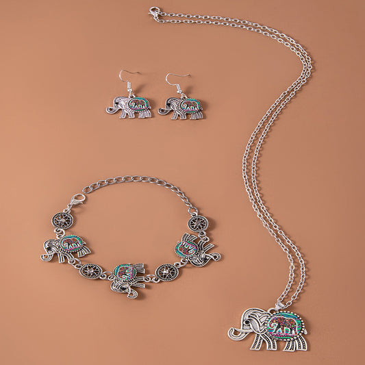 Jewelry set with elephant-themed necklace, bracelet, and earrings on a brown background