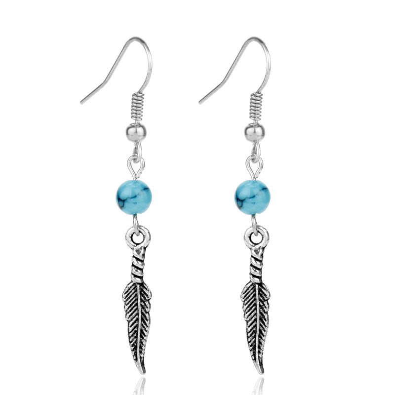 Silver earrings with turquoise beads and feather designs on a white background