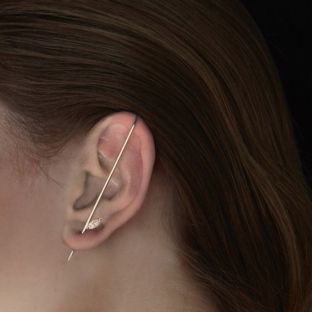 Close-up of an ear with a gold earring against a dark background