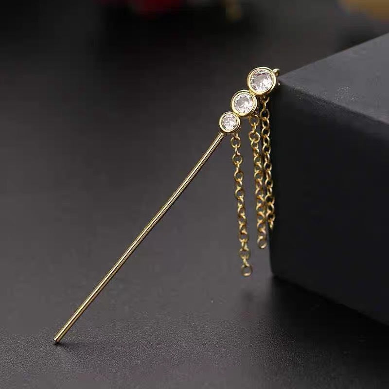Gold hairpin with three crystals on a dark surface