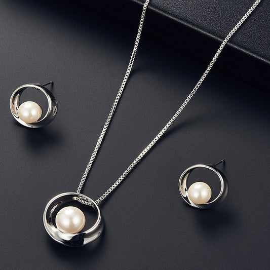 Pearl necklace and earrings set on a dark surface