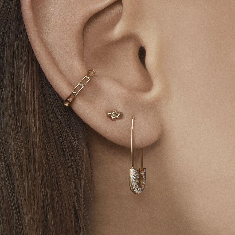Close-up of an ear wearing gold earrings with a soft focus background