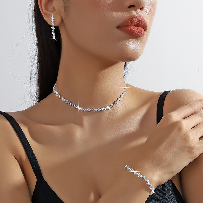Woman wearing a diamond necklace, earrings, and bracelet on a plain background