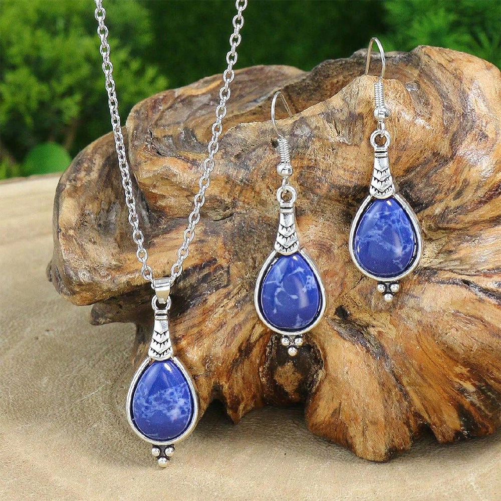 Jewelry set with blue teardrop pendants on a wooden surface