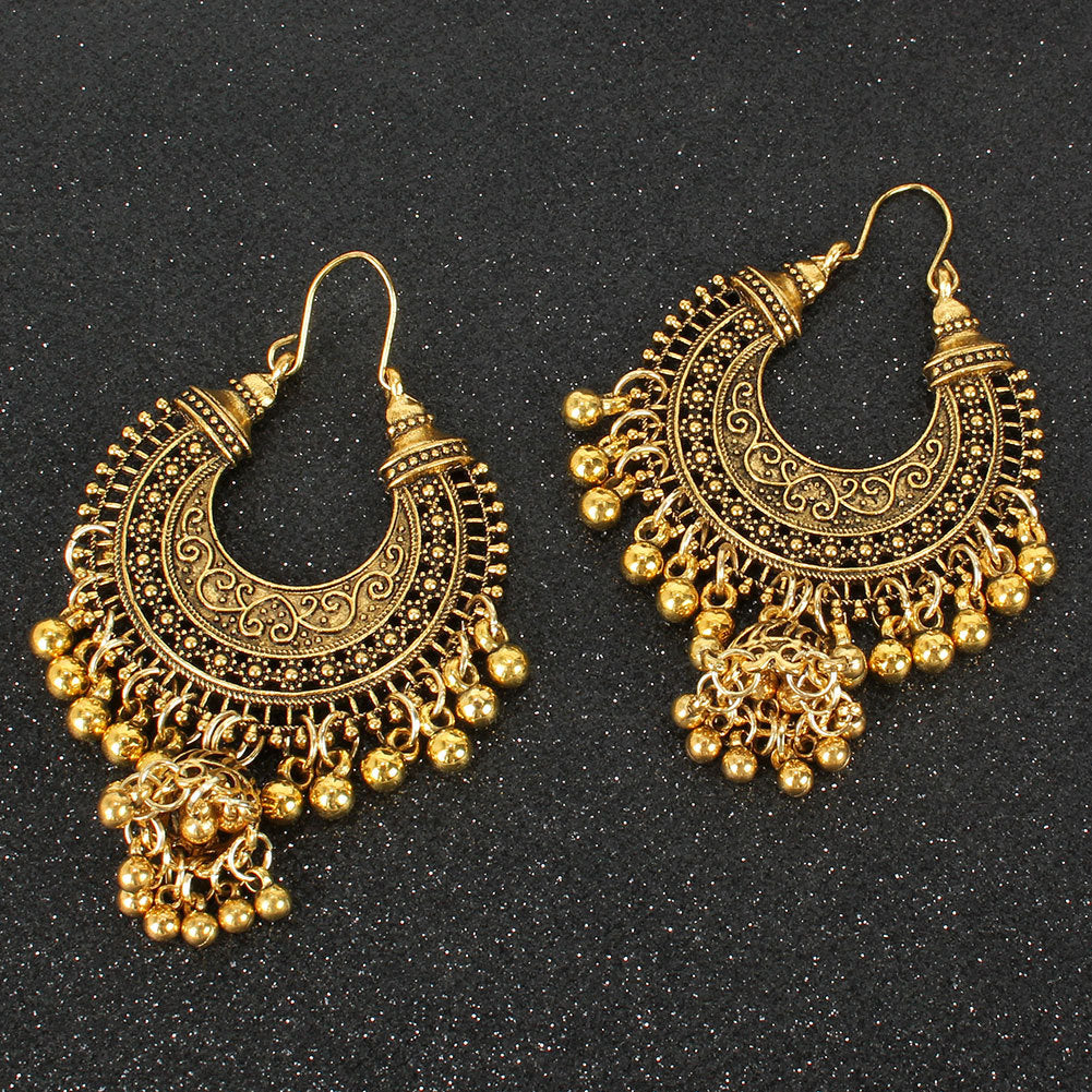 Pair of gold hoop earrings with intricate designs on a black background