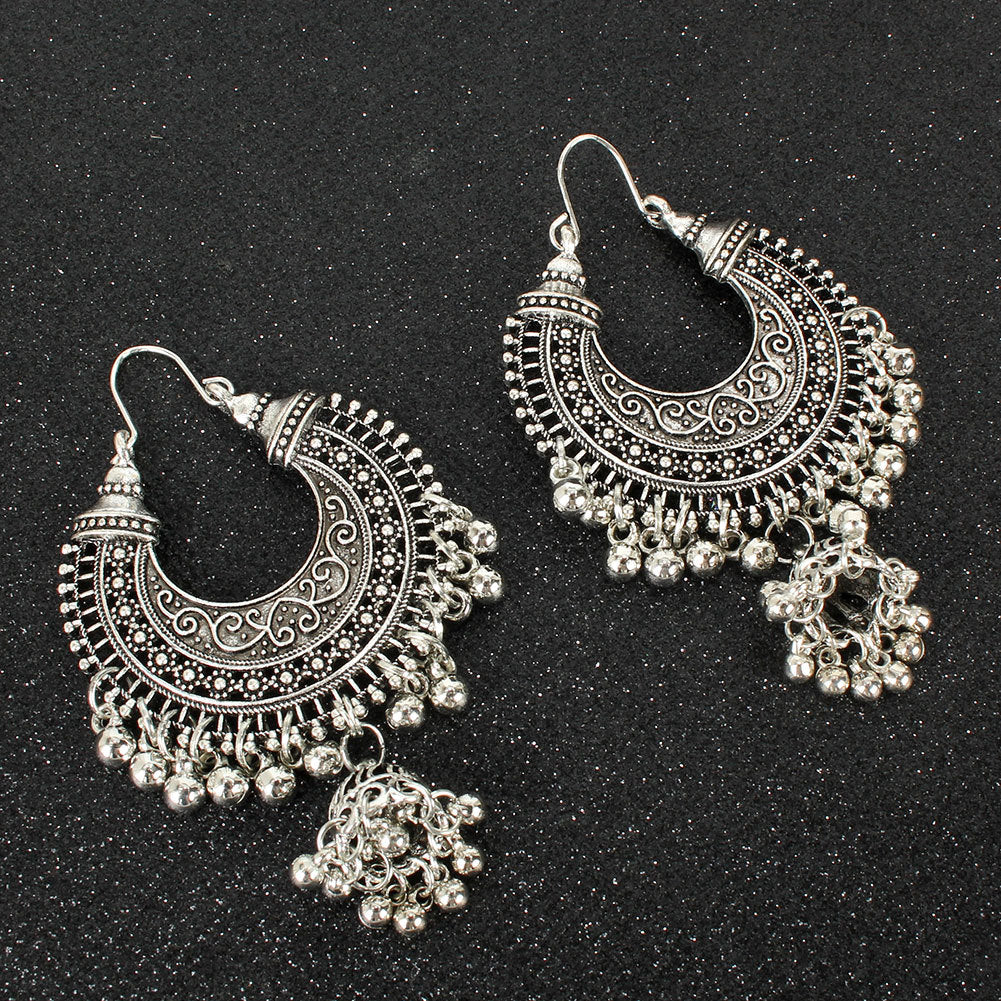 Pair of silver hoop earrings with intricate designs on a black background