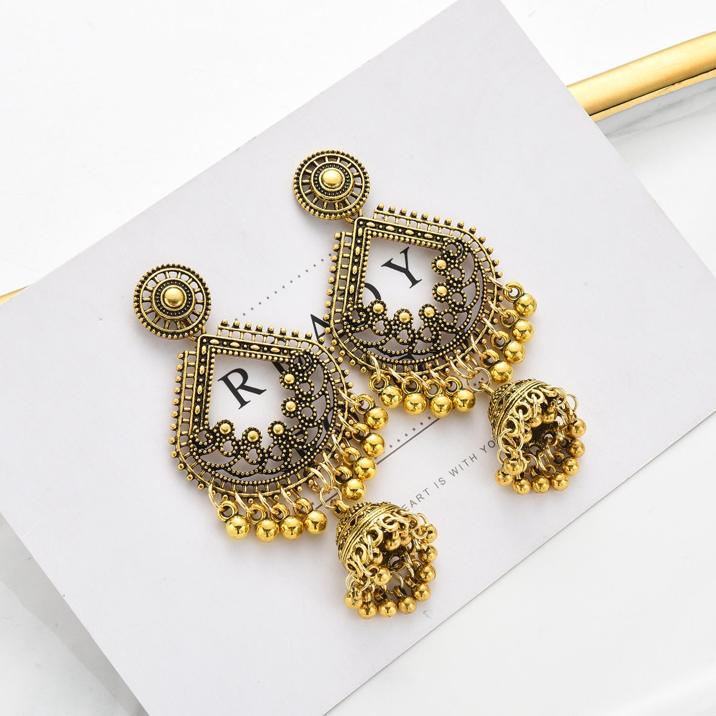Gold earrings with intricate designs on a white surface