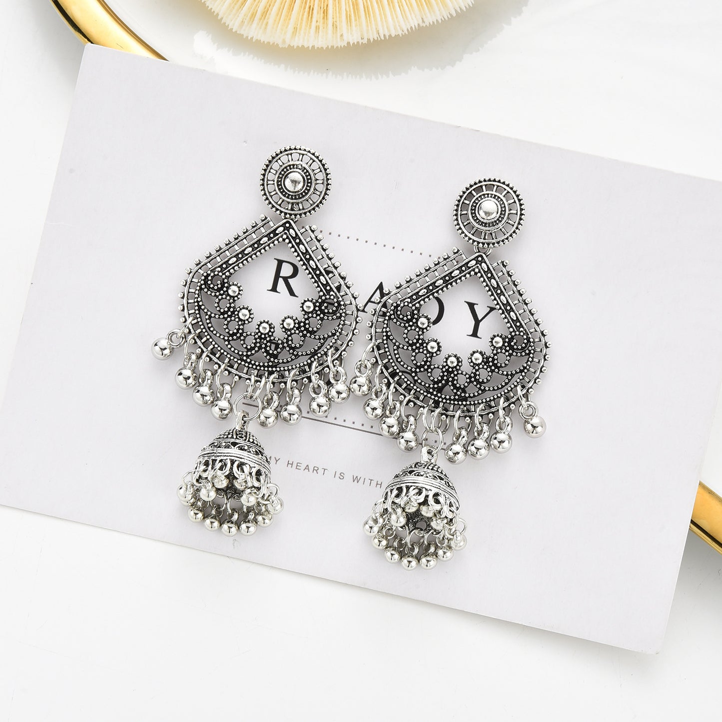 Silver earrings with intricate designs on a white card