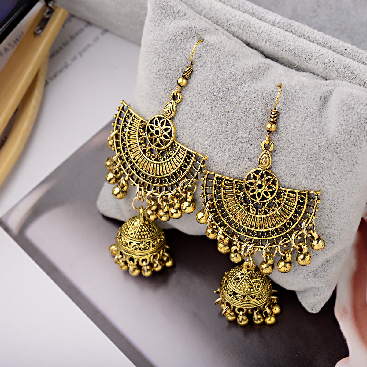 Gold earrings with intricate designs on a gray surface