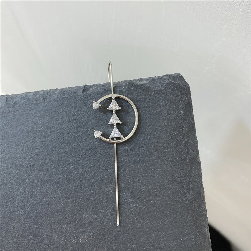 Silver earrings with geometric design on a gray slate surface