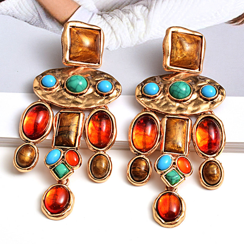 Colorful earrings with gold, red, and blue stones on a white background