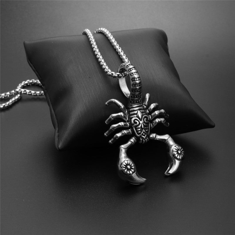 Silver scorpion pendant necklace on a black cushion with a dark background