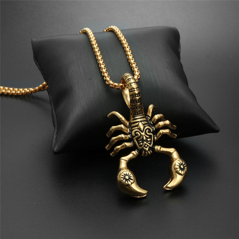 Gold scorpion pendant necklace on a black cushion against a dark background
