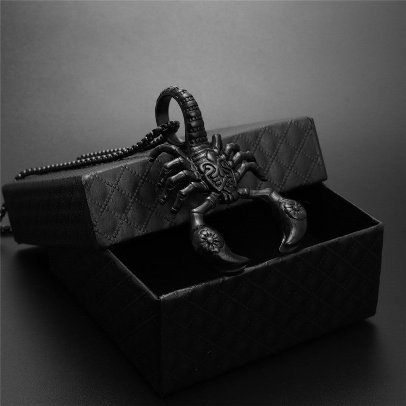 Black scorpion-shaped keychain in an open box on a dark background