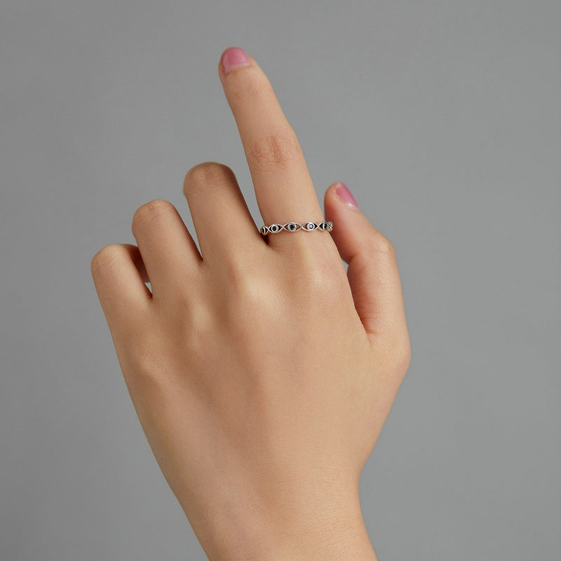 Hand wearing a silver ring on a gray background