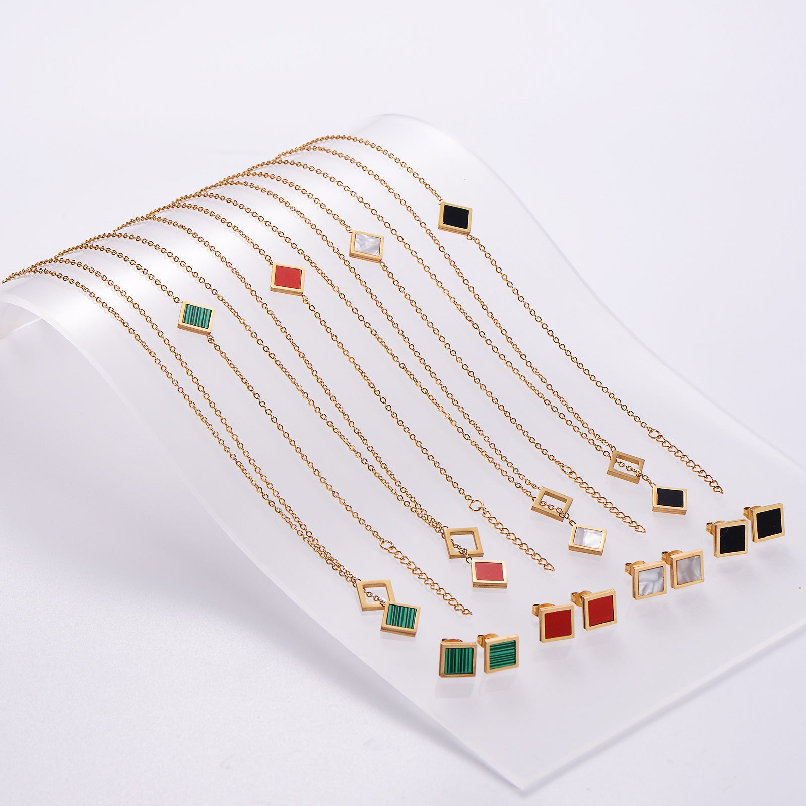 Gold necklaces with various colored pendants on a white background
