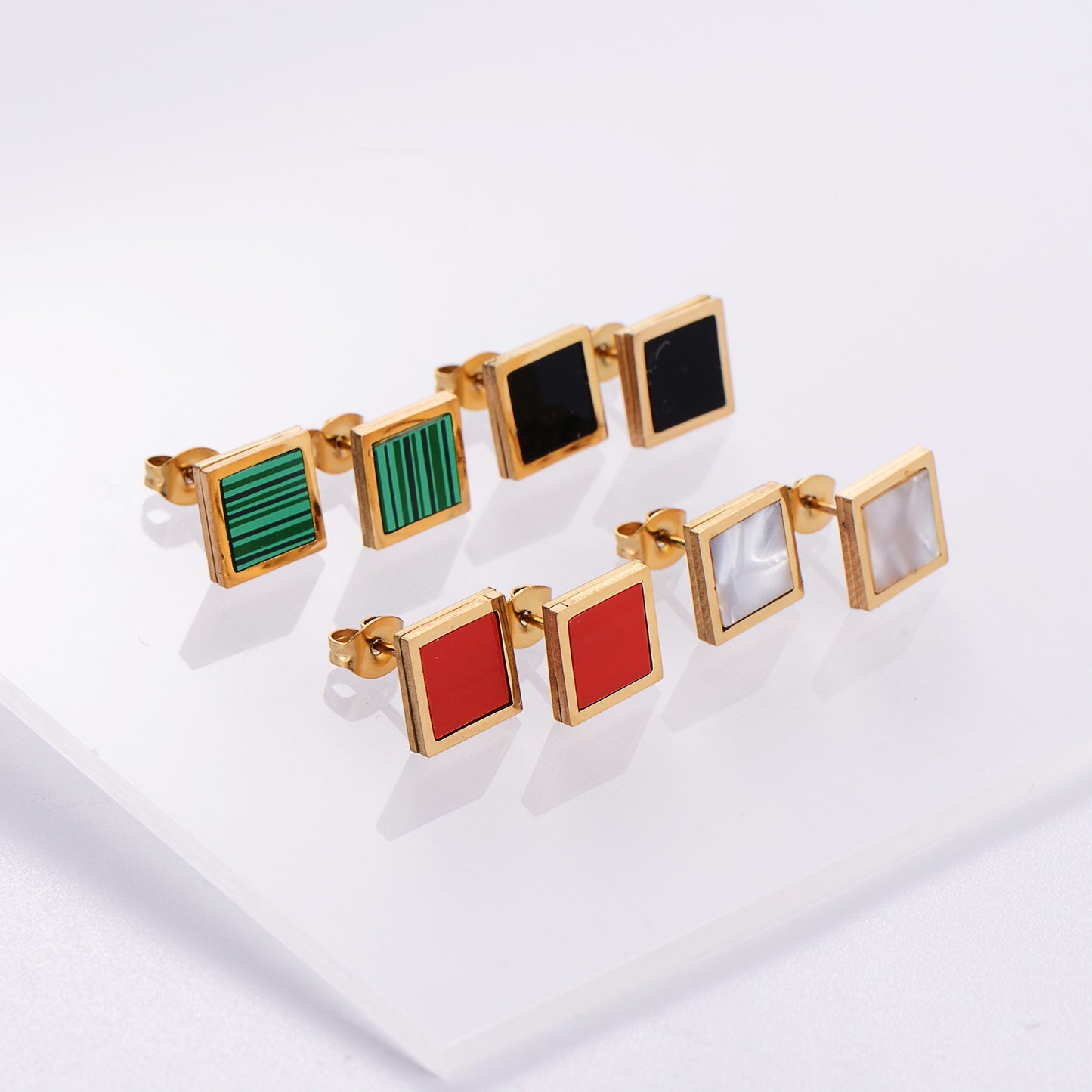 Set of square-shaped earrings with colorful centers on a white background
