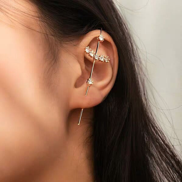Close-up of an ear with gold earrings against a neutral background