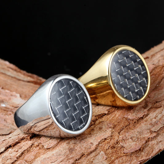 Two rings, one gold and one silver, with carbon fiber pattern on a wooden surface.